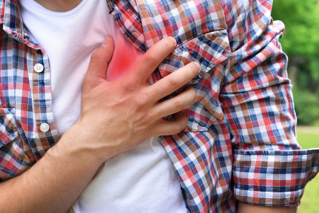 man clenching chest, heart disease concept