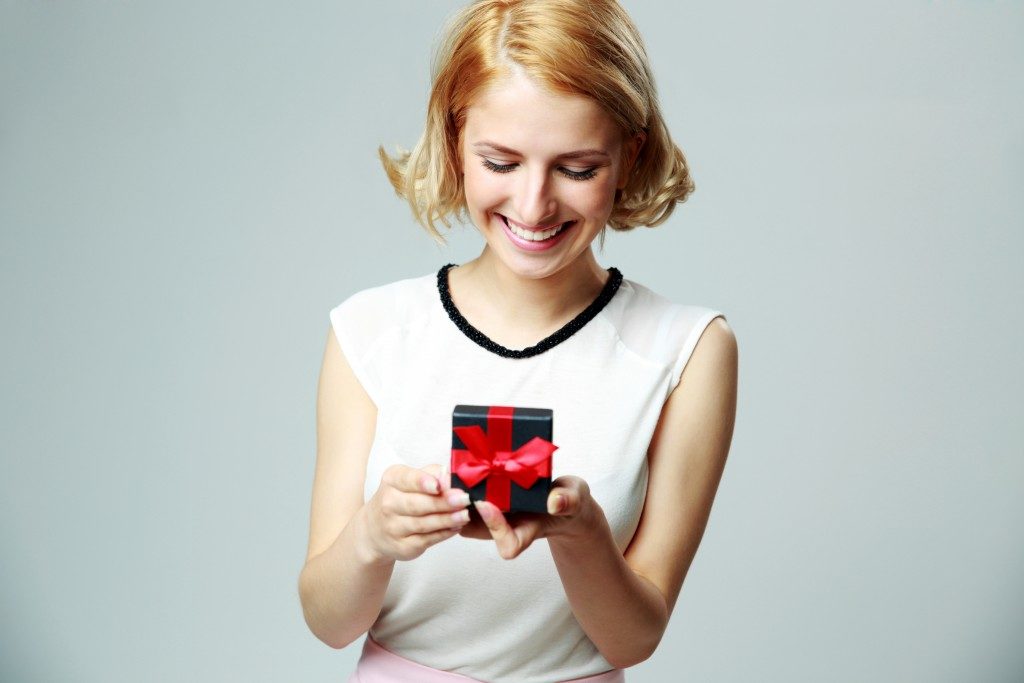 Smiling beautiful young woman holding an open jewelry gift box