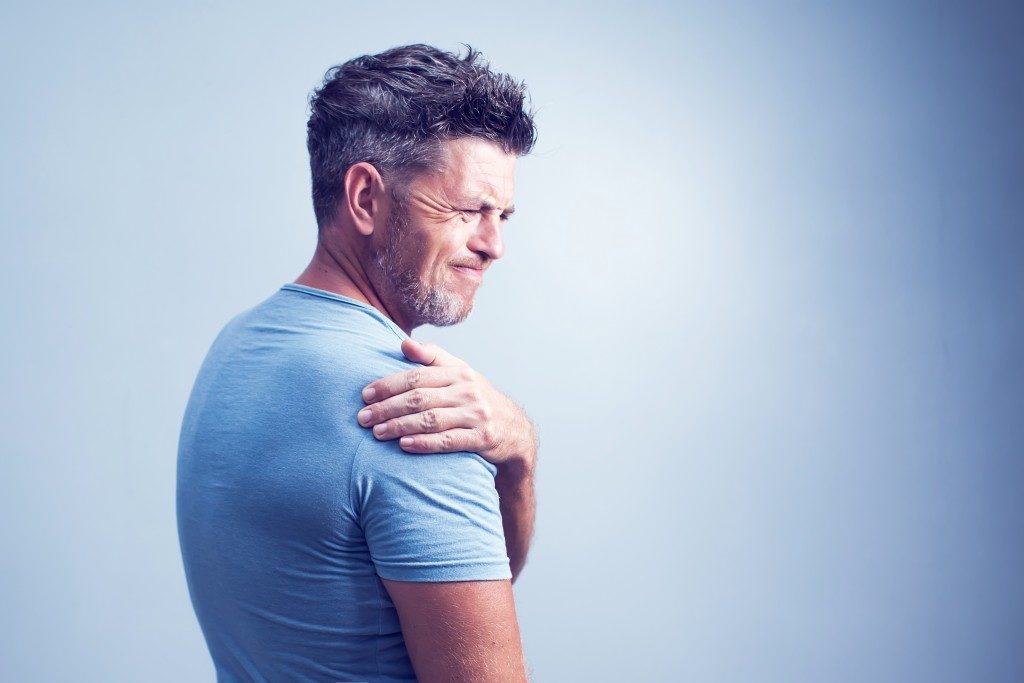 man experiencing muscle pain in the shoulder area