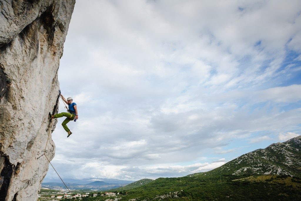 male climber hanging by a cliff