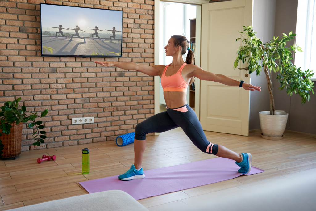 Young woman performing yoga while watching an online training exercise.