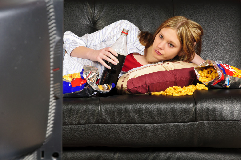 drinking soda eating chips while lying and watching tv