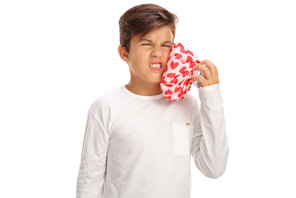 A child with toothache applying cold compress